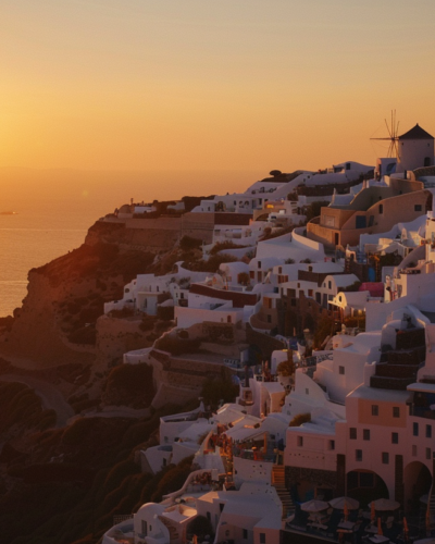 The sunset over the white-washed buildings of Oia, Santorini, with the Aegean Sea in the background and tourists enjoying the view.